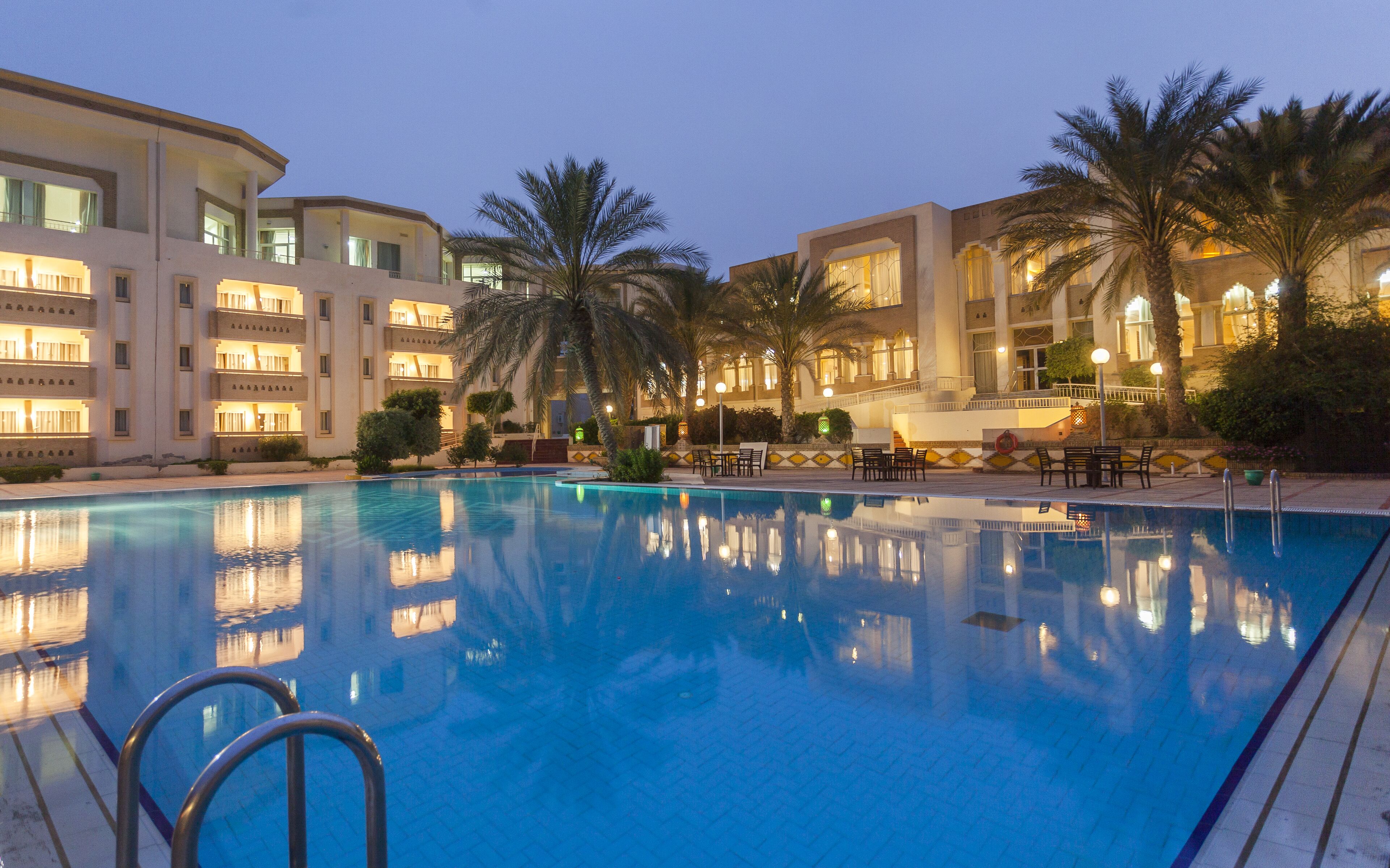A swimming pool with a clear view of the surrounding hotel buildings and palm trees.