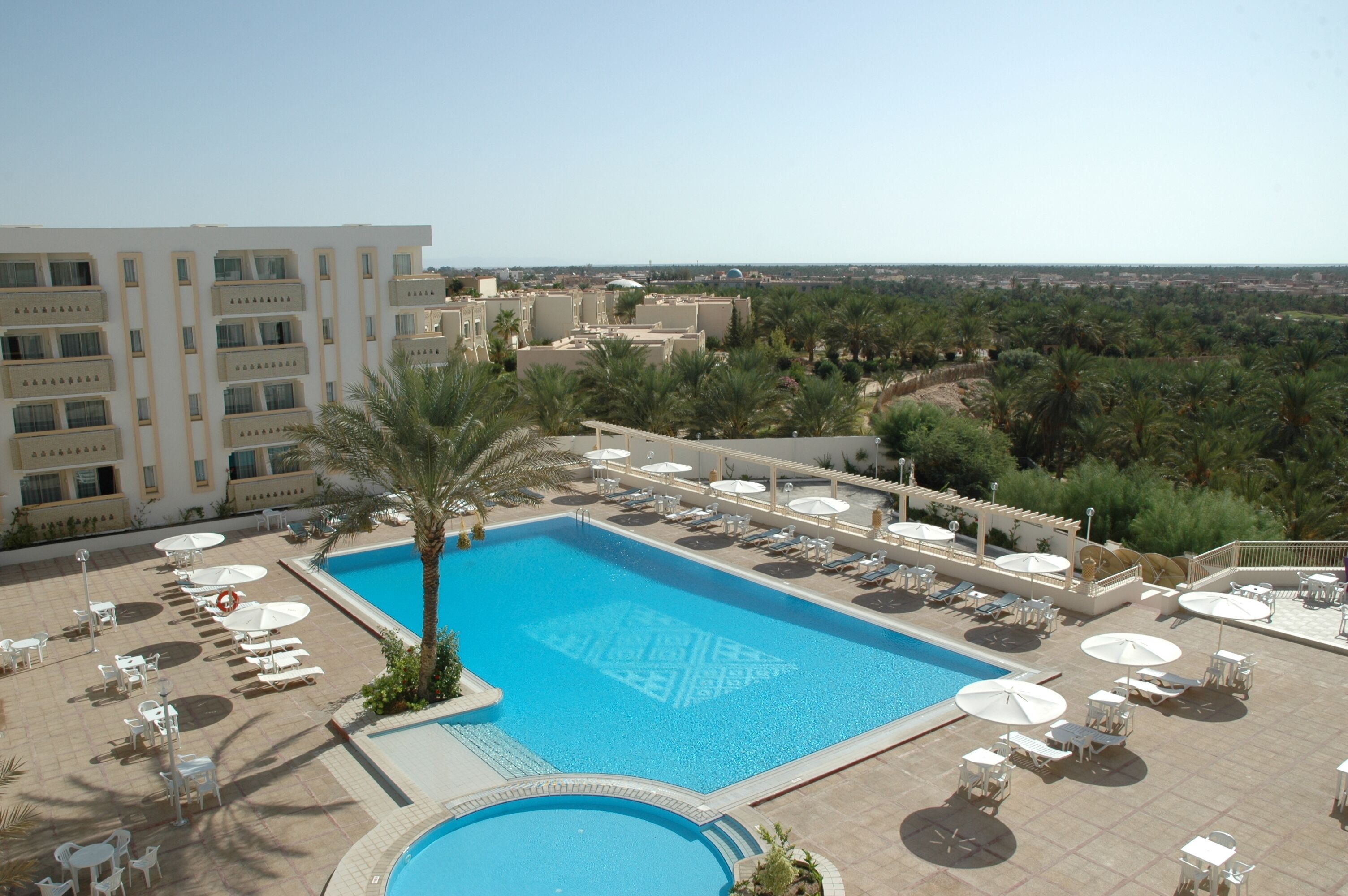 A hotel pool area with sun loungers, umbrellas, and a large pool.
