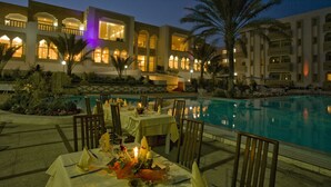 A poolside dining area with tables set for a meal, overlooking a swimming pool. - El Mouradi Tozeur (Tozeur)