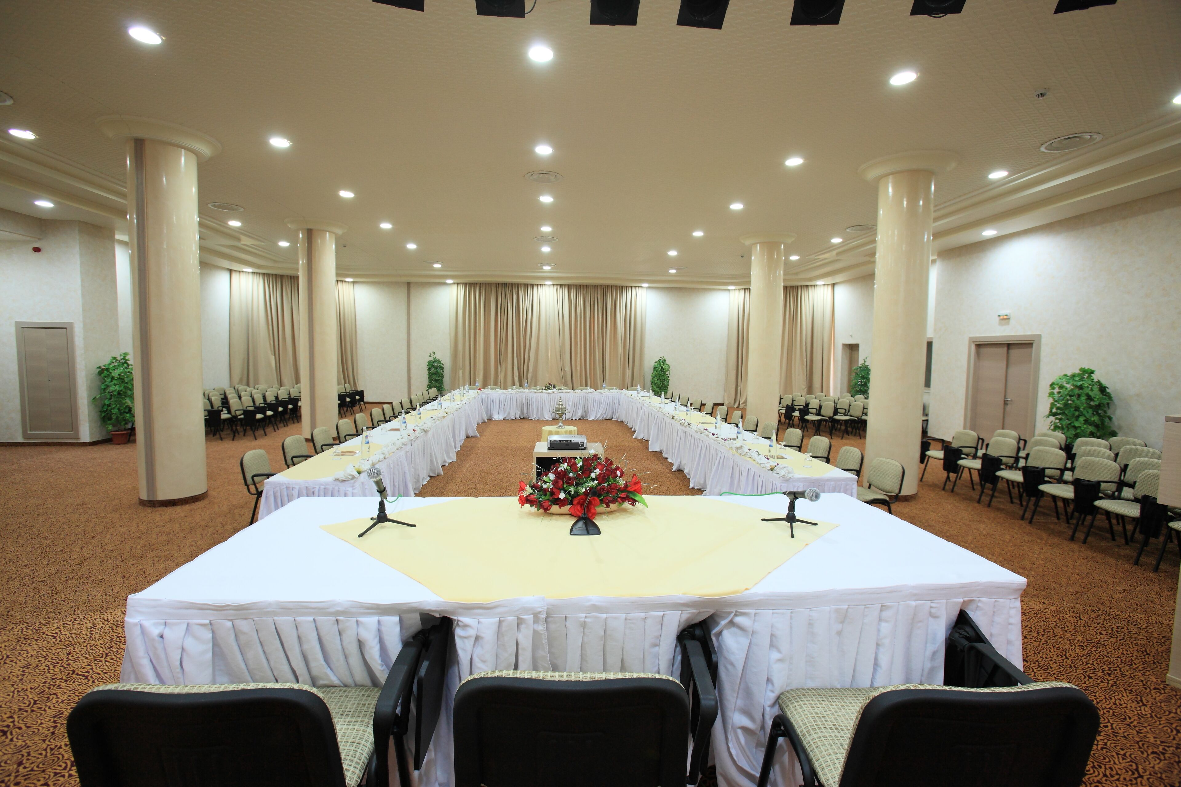 A conference room with a long table, chairs, and a microphone stand.