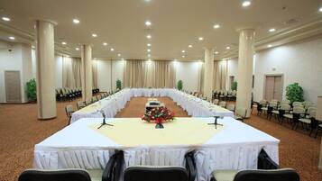 A conference room with a long table, chairs, and a microphone stand.