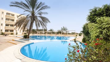 Relax by the pool surrounded by lush greenery and comfortable lounge chairs.