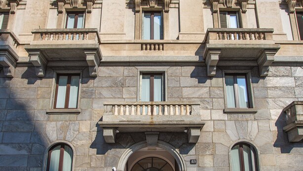 Un edificio histórico con una entrada imponente, múltiples ventanas y detalles arquitectónicos de estilo clásico.