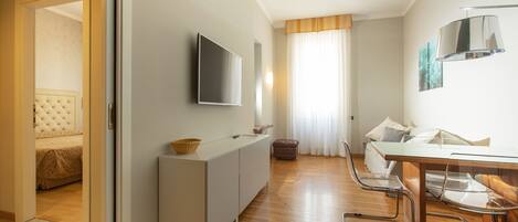 Una habitación de hotel moderna con cama, escritorio, silla, televisor y ventana con cortinas.