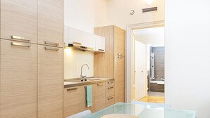 Una cocina moderna con armarios de madera, una mesa de vidrio y un lavamanos de acero inoxidable.