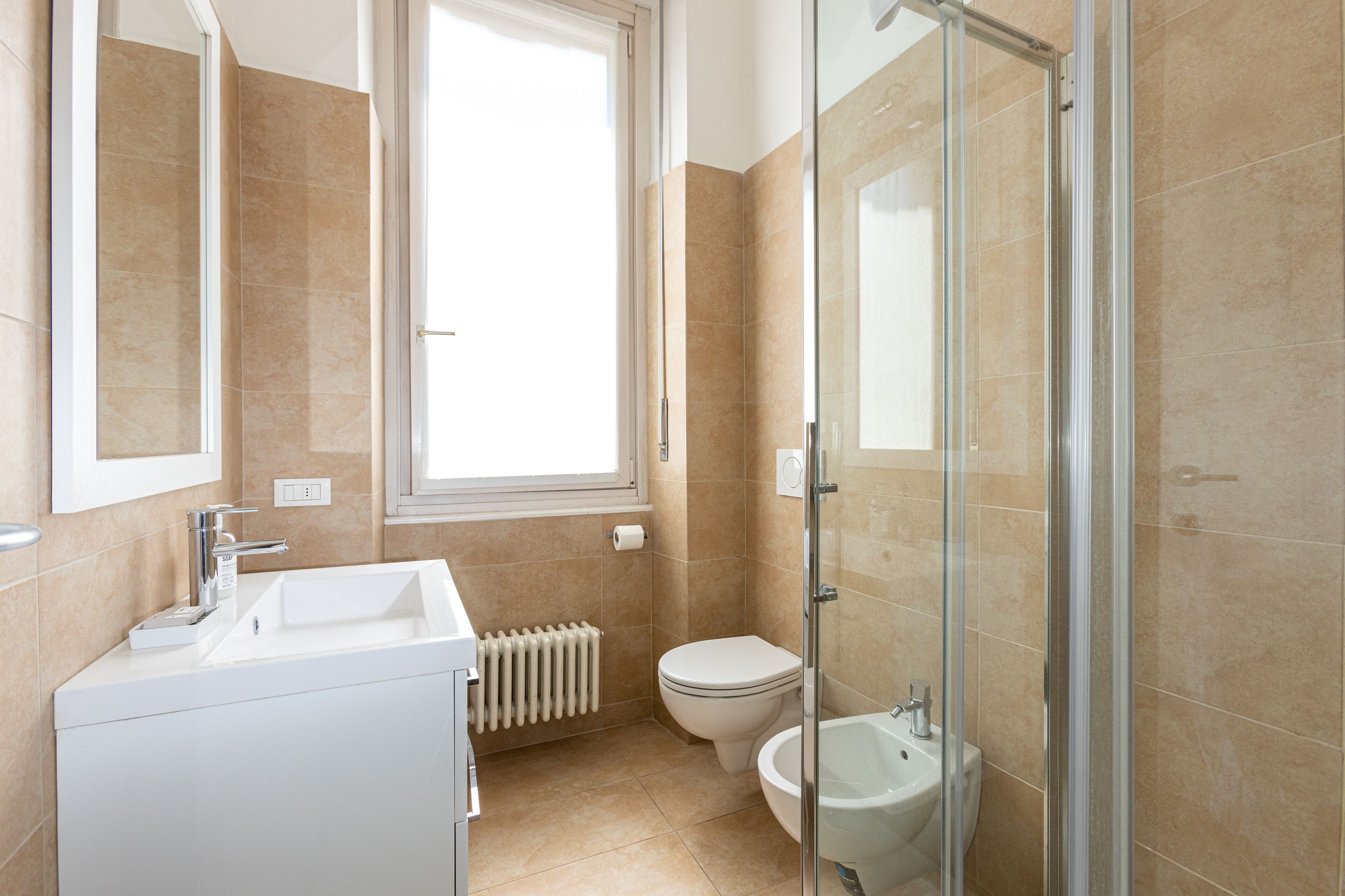 Ein modernes Badezimmer mit Waschbecken, Toilette, Bidet und Duschkabine.