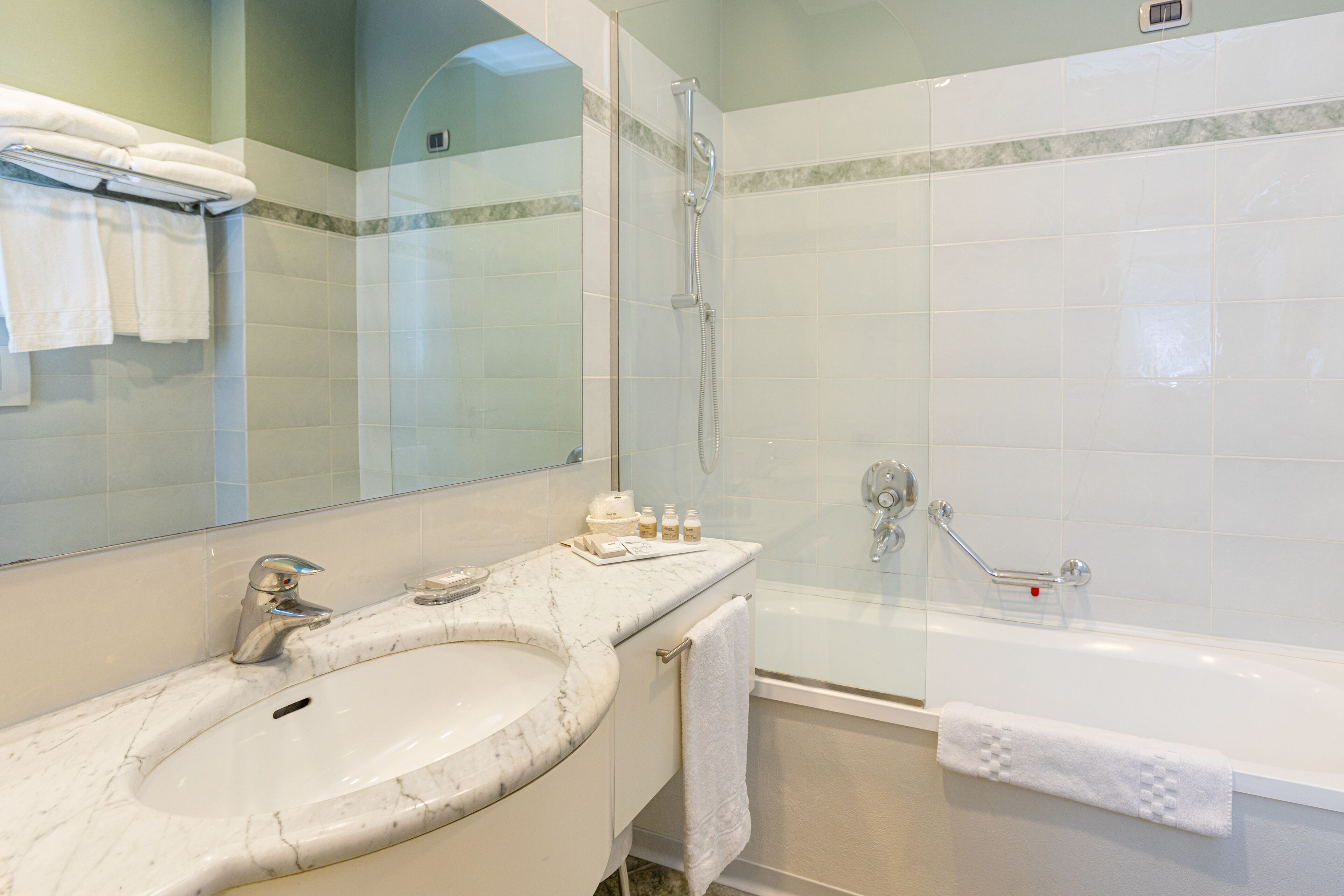 Une salle de bain avec un lavabo en marbre, une douche à parois de verre et une baignoire blanche.