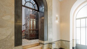 Una escalera de mármol con barandilla de metal que lleva a una puerta con panel de vidrio.