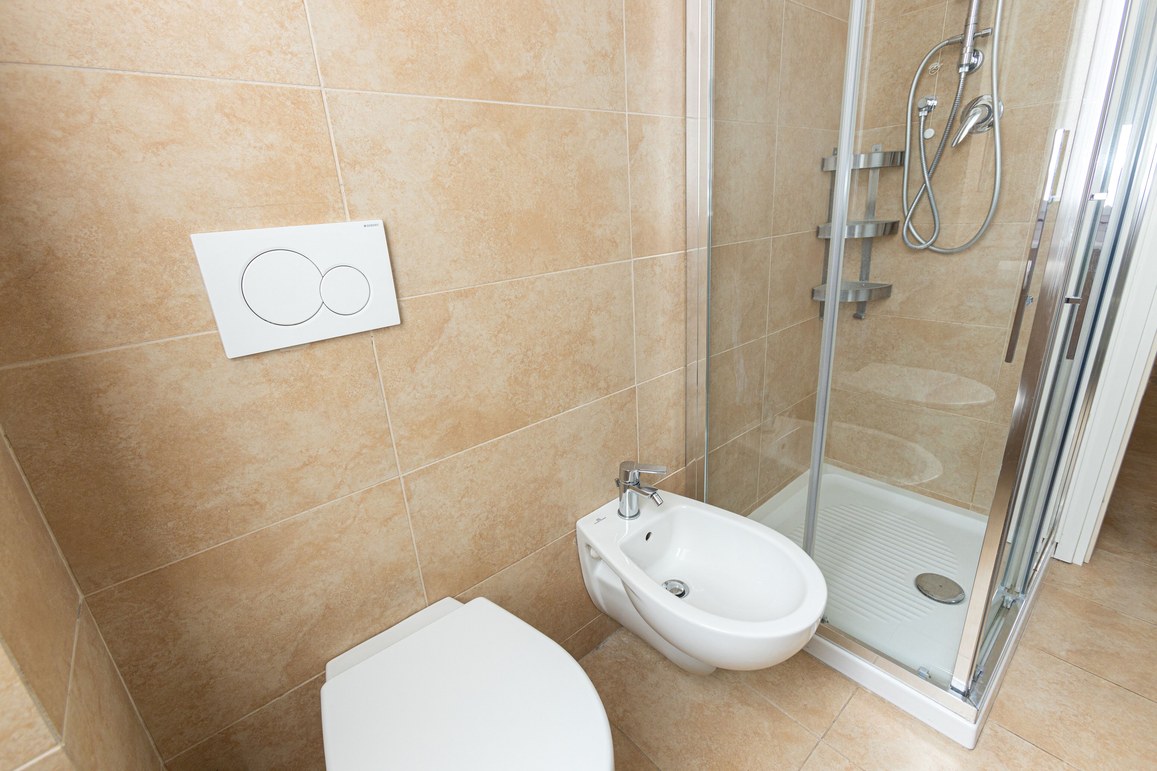 Un baño moderno con inodoro, bidé y ducha con cerramiento de vidrio.