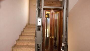 A staircase with a wooden door at the top, a metal railing, and a control panel.