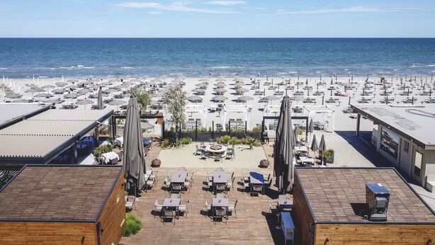 A rooftop terrace with outdoor seating and a view of the beach. - Majestic (Cervia)