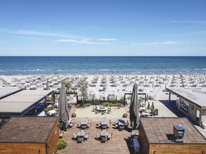 A rooftop terrace with outdoor seating and a view of the beach. - Majestic (Cervia)