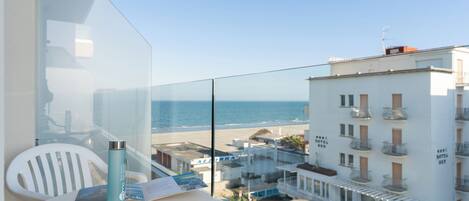 A balcony with a clear view of the beach and hotel buildings.
