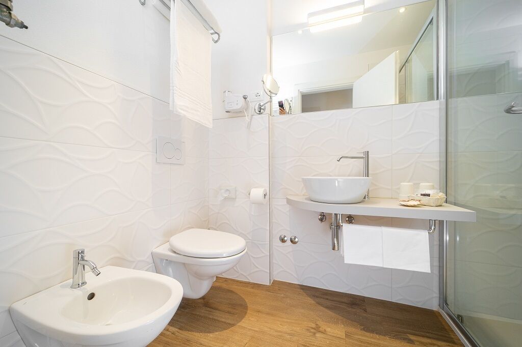 A modern bathroom with a white sink, toilet, and a glass shower enclosure.