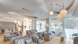 A modern interior with grey upholstered sofas, wooden flooring, and pendant lighting. - Majestic (Cervia)