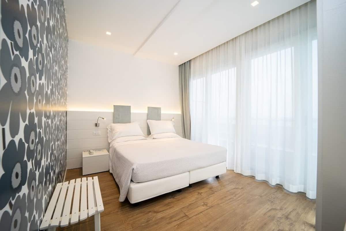 Un dormitorio moderno con una cama grande, mesitas de noche y un banco.
