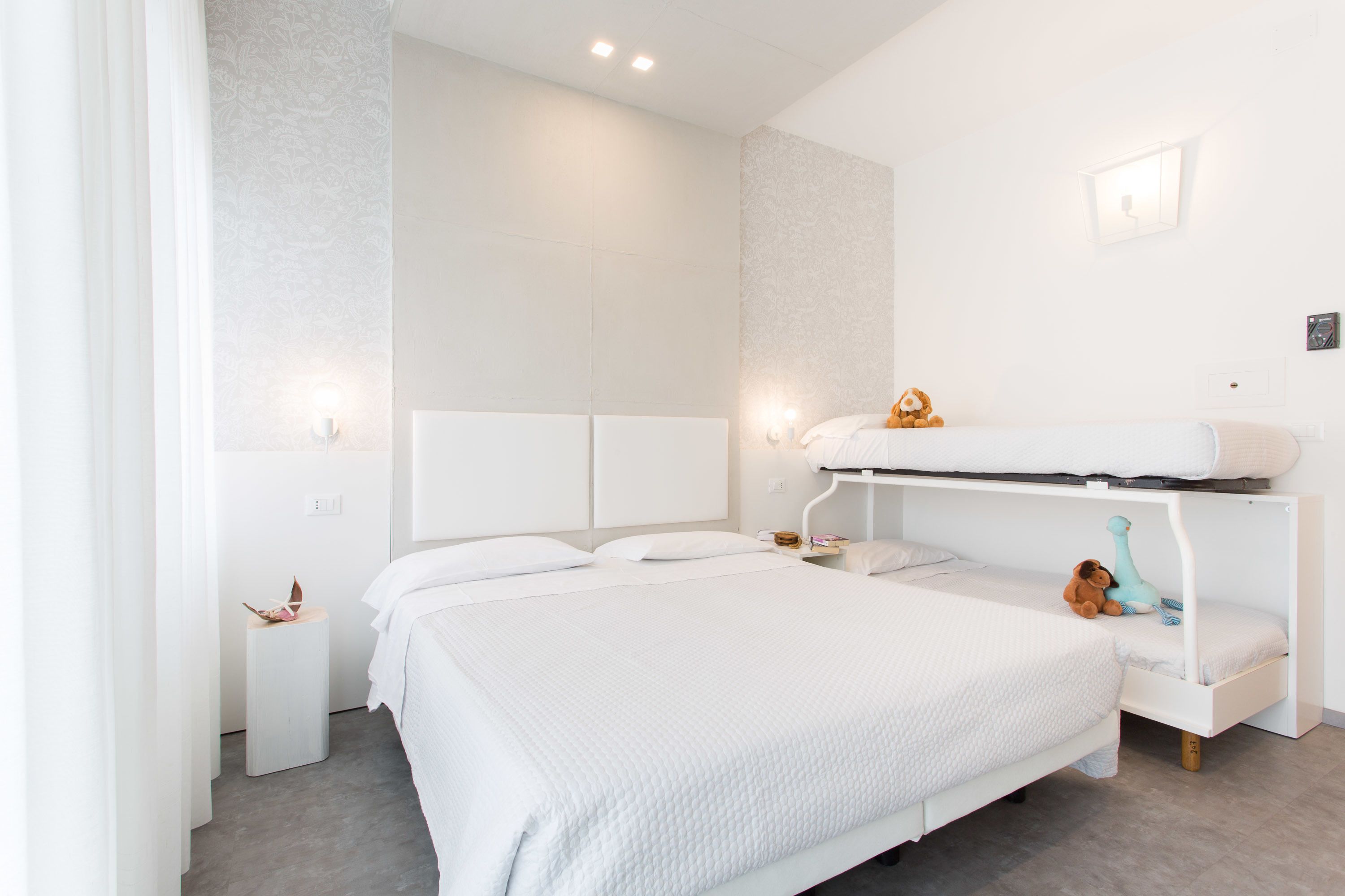 Un dormitorio moderno con una litera, una mesita de noche y un buró.