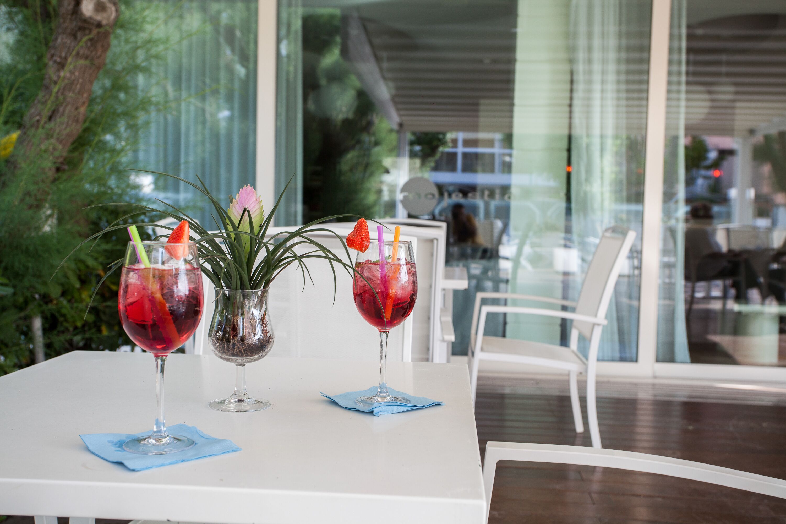 A table with two wine glasses, each with a blue napkin and a decorative flower.