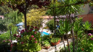 Ein Garten mit verschiedenen Pflanzen und Blumen, einem Kiesweg und einem blauen Pool.