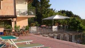 Eine Terrasse mit Liegestühlen, einem Pool und einem überdachten Bereich mit weißem Baldachin.