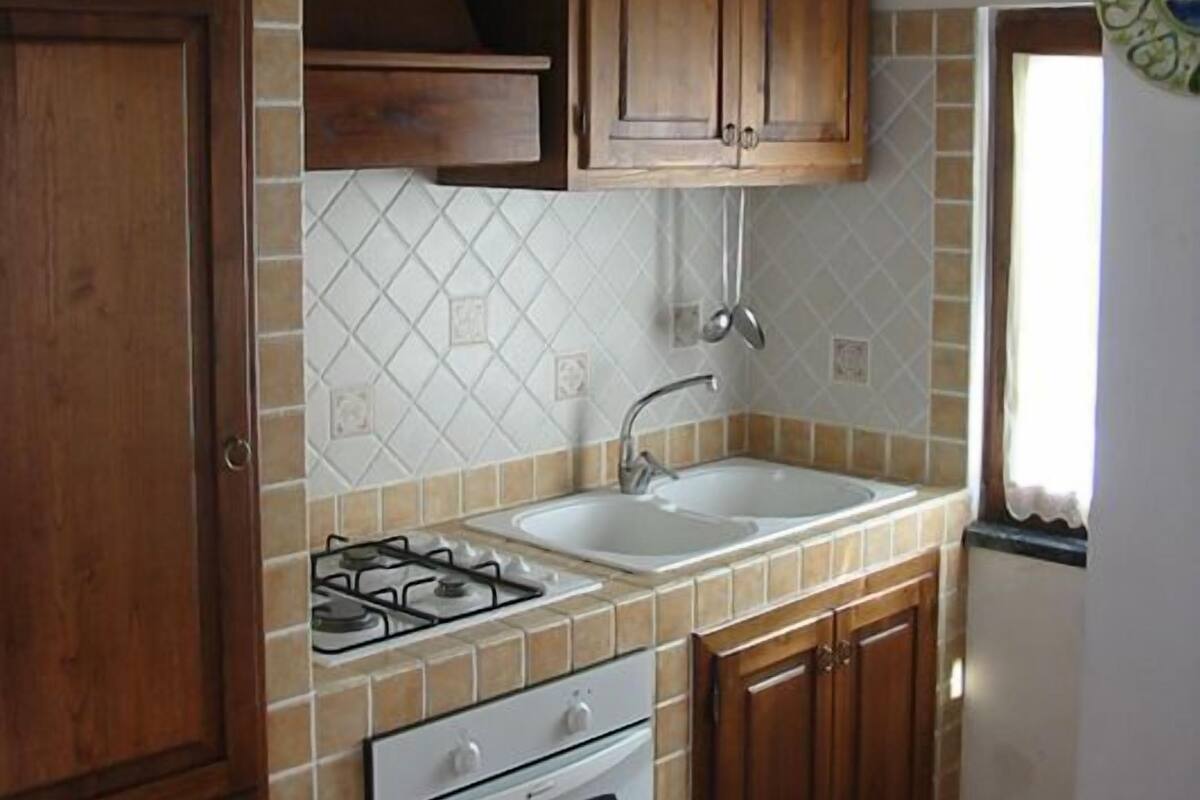 A kitchen with wooden cabinets, a gas stove, a sink, and a tiled backsplash.