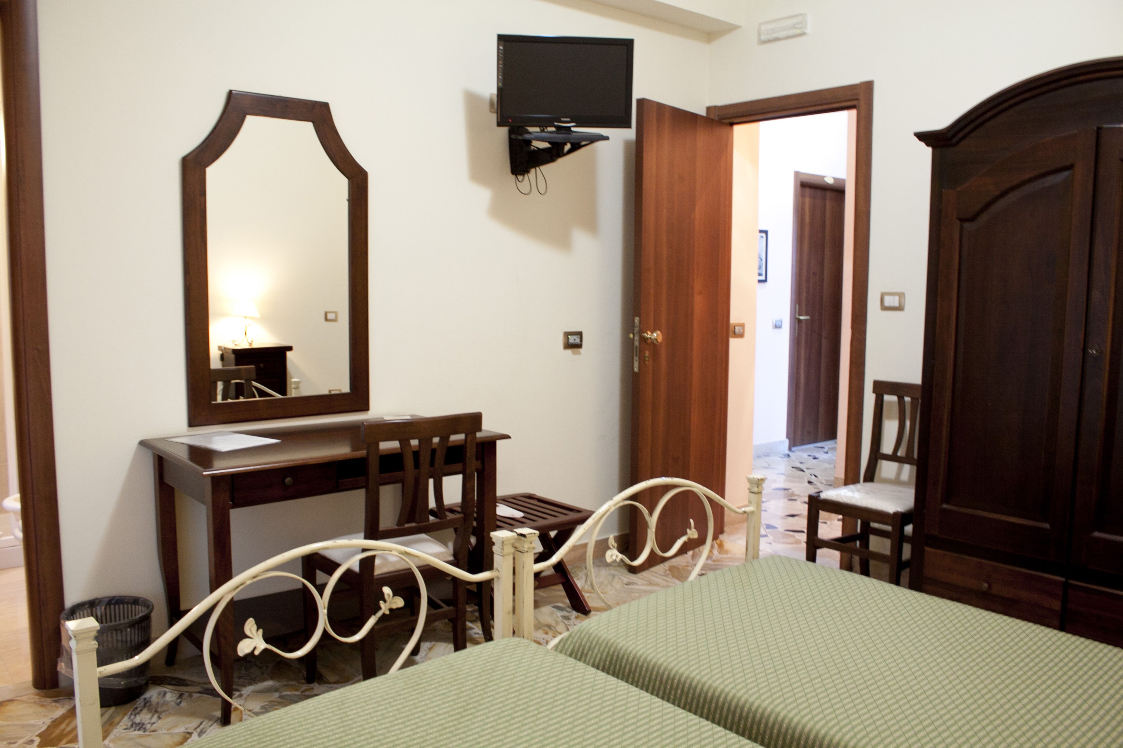 A bedroom with a bed, a dresser, a mirror, a television, and a chair.