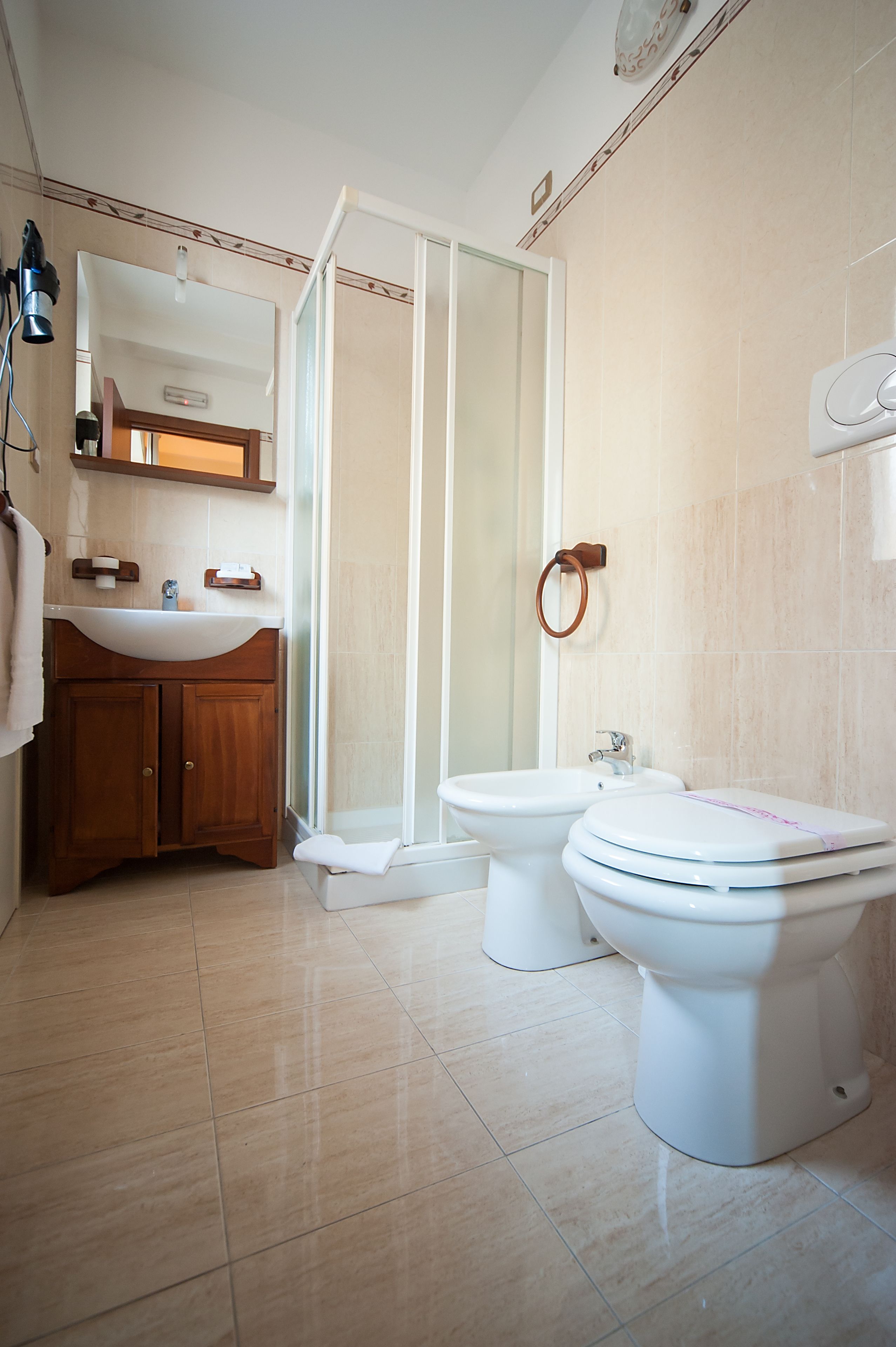 A bathroom with a wooden vanity, a shower, and two toilets.