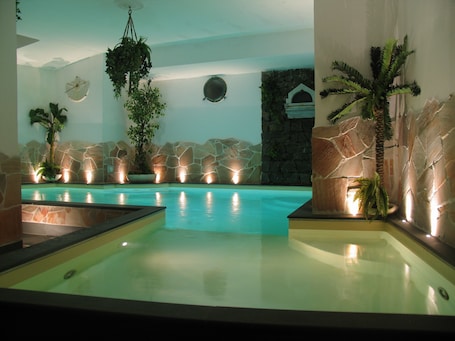 Una piscina techada, una piscina al aire libre, sombrillas