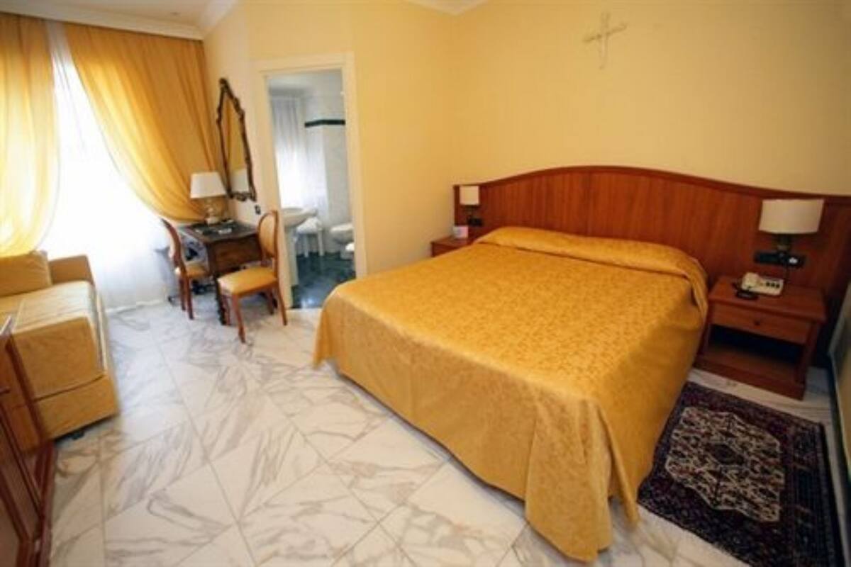 Une chambre d’hôtel comprenant un lit, un bureau, une chaise, une table de chevet et un miroir.