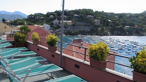 A balcony with lounge chairs and potted plants overlooking a marina with boats. - Hotel Due Mari (Sestri Levante)