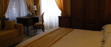 A hotel room with a bed, a desk, a chair, and a wardrobe.