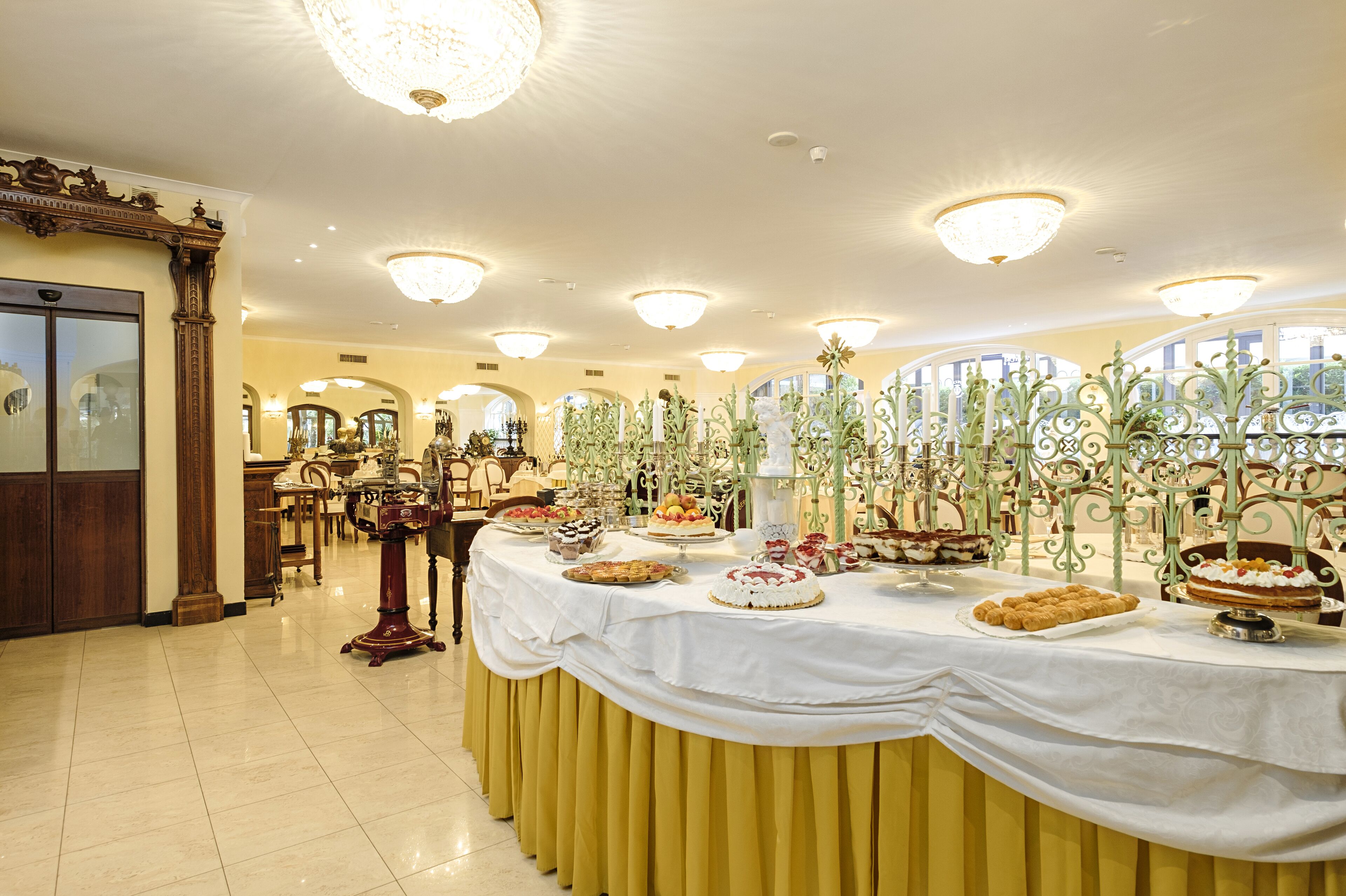 A banquet hall with a long table covered in various desserts and a chandelier.