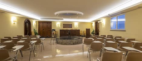 A conference room with a central fountain, multiple tables, and chairs arranged for meetings.
