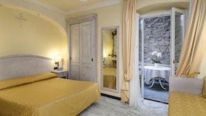 A hotel room with a bed, a nightstand, a mirror, a wardrobe, and a balcony with a table and chairs. - Hotel Due Mari (Sestri Levante)