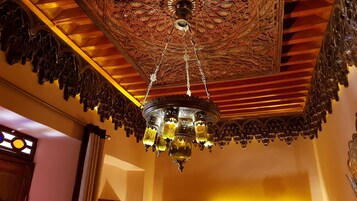 Un lampadario con diverse luci sospeso sotto un soffitto con decorazioni elaborate.