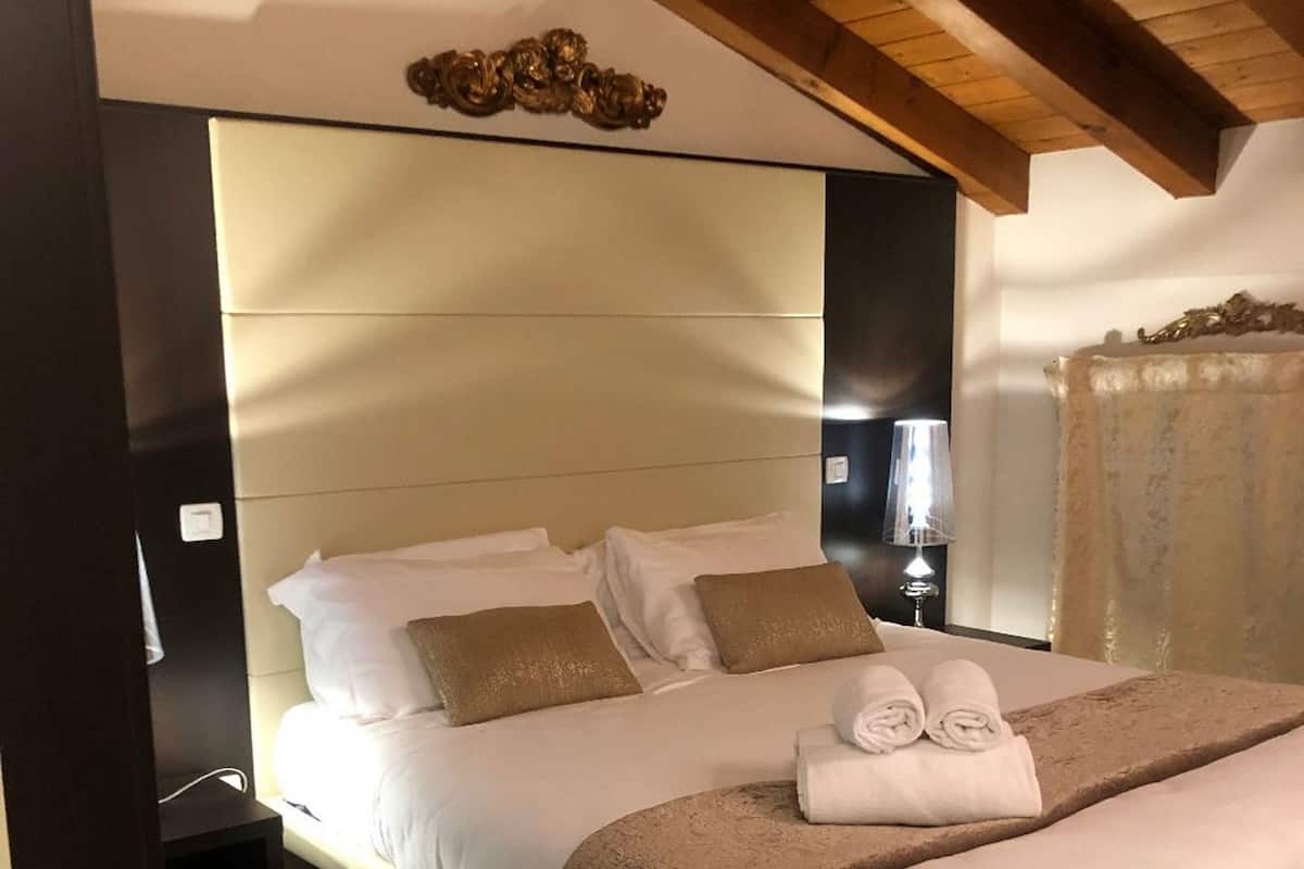 A modern bedroom with a large bed, a bedside table, and a lamp.
