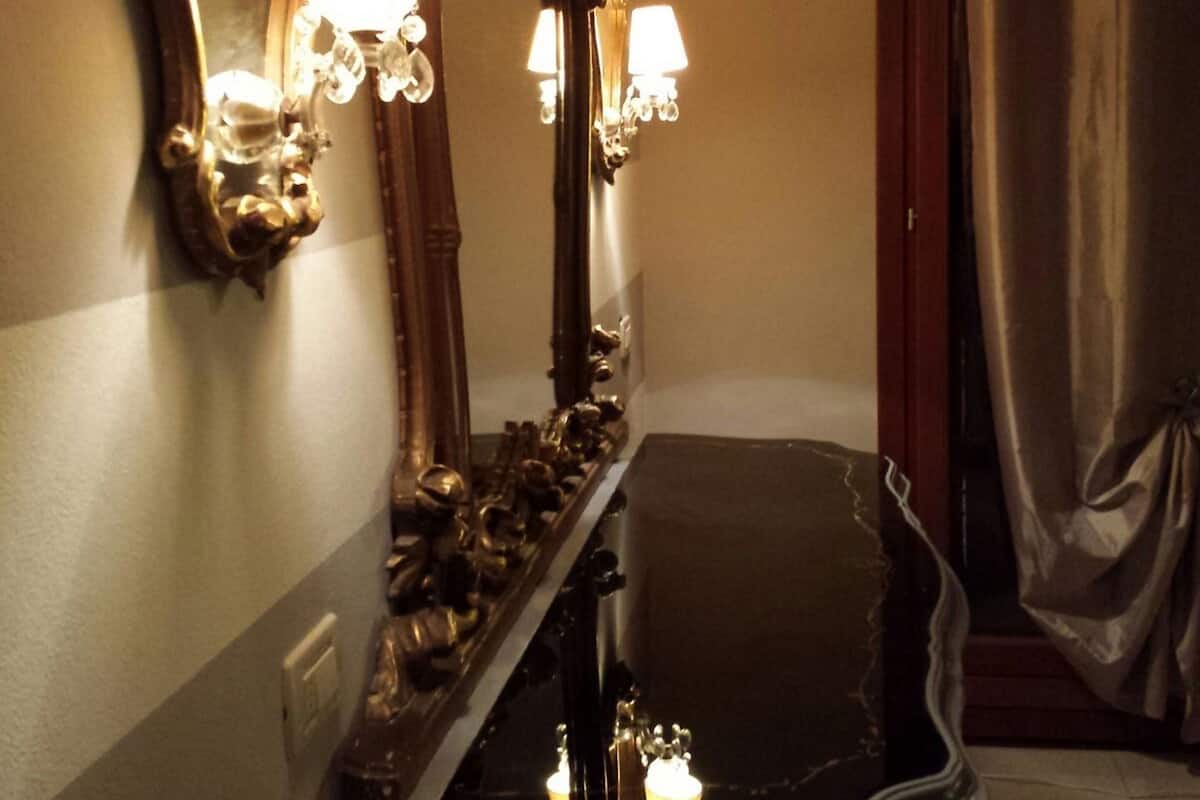 A bathroom with ornate mirrors, a bathtub, and wall-mounted sconces.