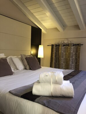 A hotel room with a large bed, multiple pillows, a bedside lamp, and a decorative headboard. - Villa Giotto Luxury Suite & Apartments (Mestre)