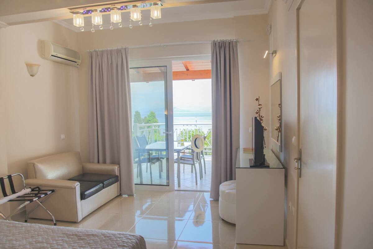A hotel room with a balcony, a sofa, a small table, and a bed.
