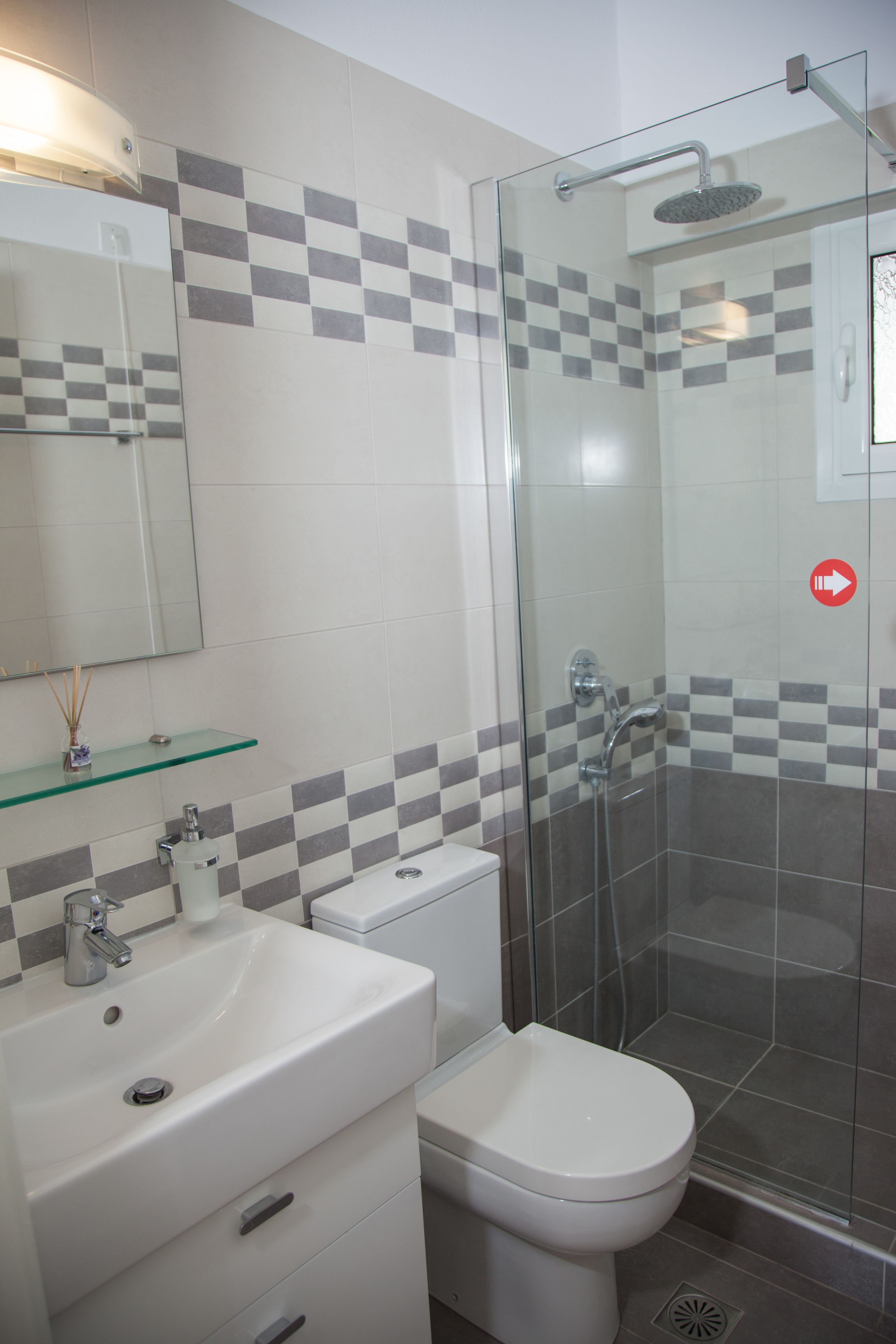 A bathroom with a glass-enclosed shower, a white sink, and a toilet.