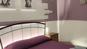 A bedroom with a bed, a nightstand, a lamp, and wall art.