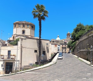 A cobblestone street leading to a historic building with a dome and bell tower.
