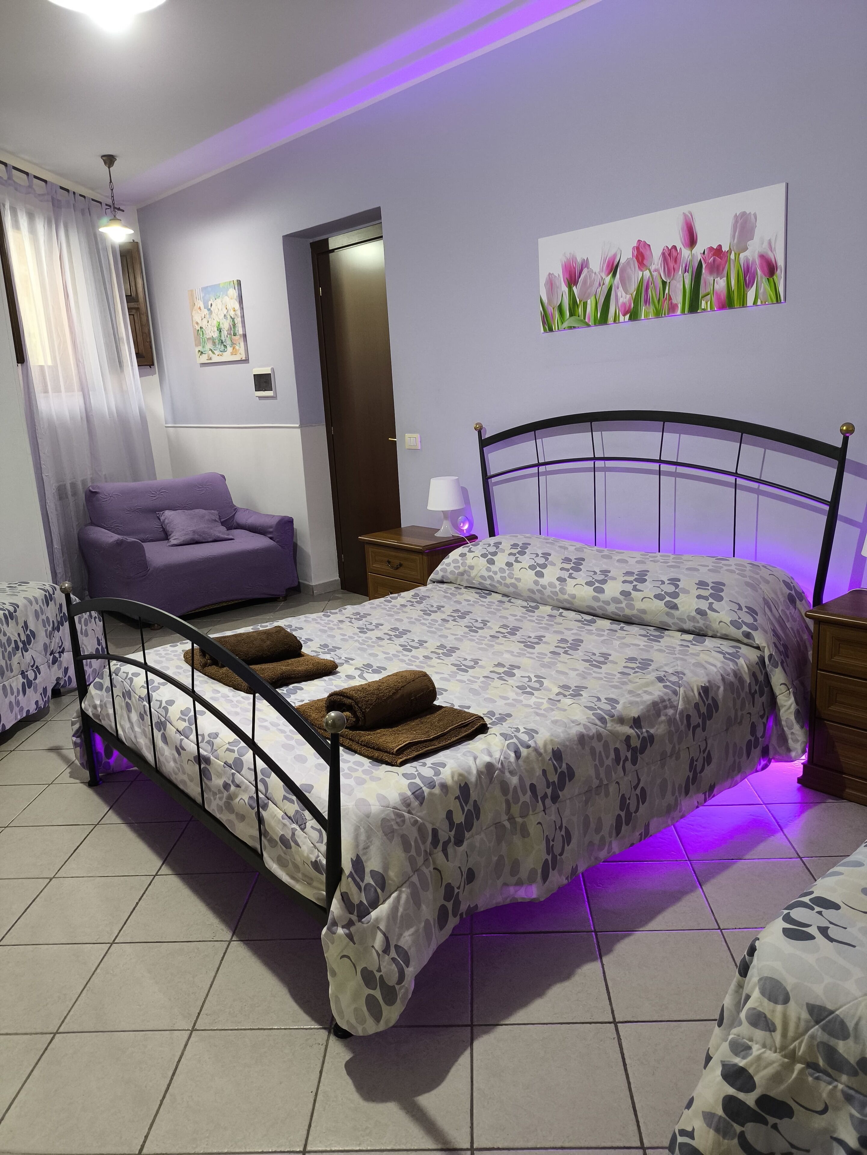 Ein Schlafzimmer mit einem Bett, einem Sofa, einem Nachttisch, einer Lampe und einem Bild an der Wand.