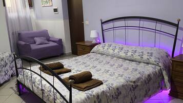 Ein Schlafzimmer mit einem Bett, einem Sofa, einem Nachttisch, einer Lampe und einem Bild an der Wand.