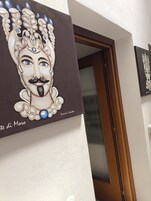 A wall with a framed artwork depicting a stylized face with a mustache and a blue gem.