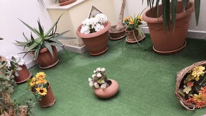 Diverse piante e fiori in vaso disposti su una superficie di erba sintetica verde.
