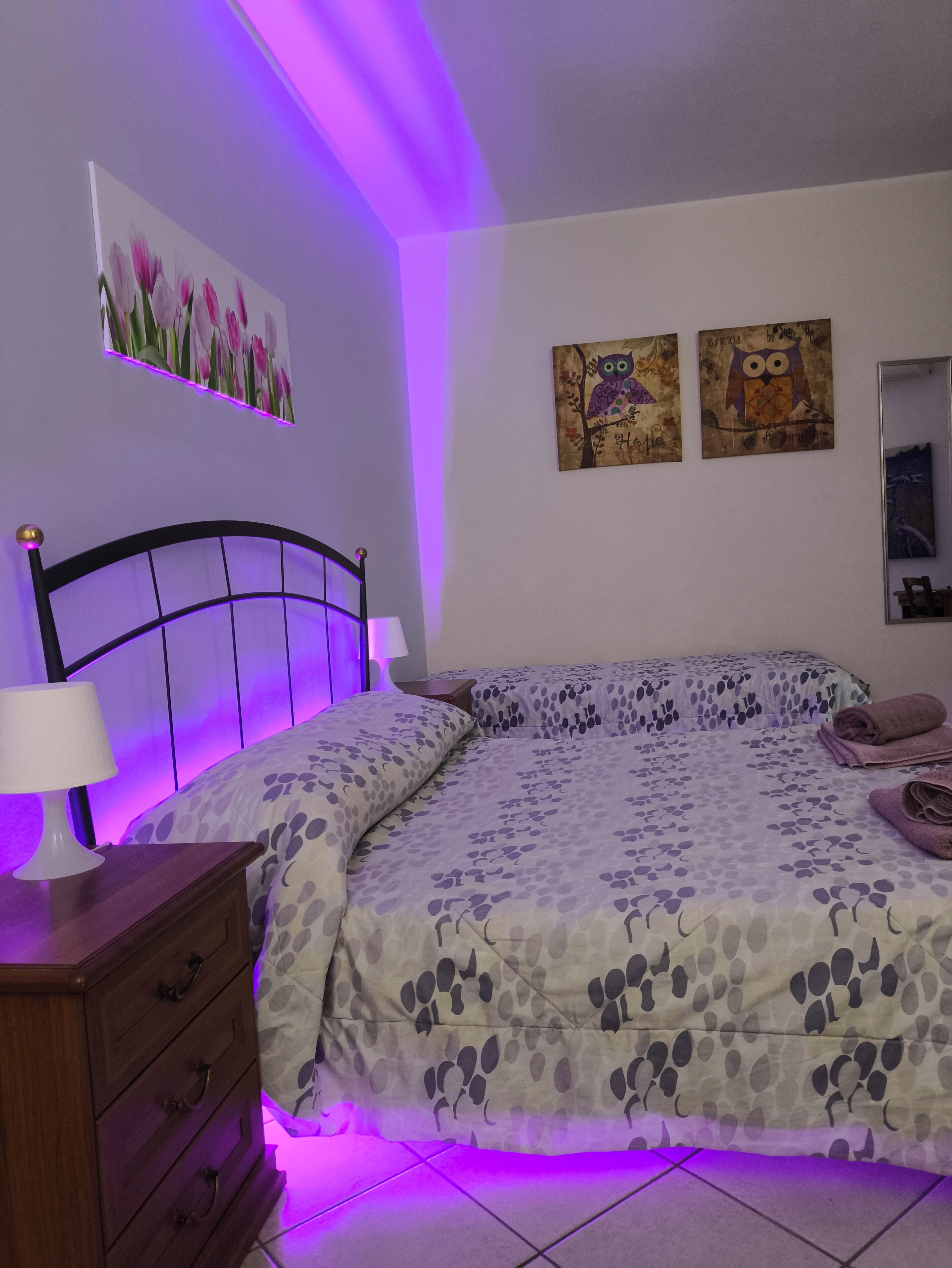 Una camera da letto con un letto, un comodino, una cassettiera e decorazioni a parete.