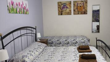 Une chambre avec deux lits, une table de chevet, une commode et des œuvres d’art murales.