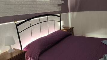 Un dormitorio con cama, mesita de noche, lámpara y decoración en la pared.