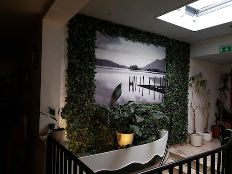 A wall with a large photograph of a lake and mountains, surrounded by green foliage.